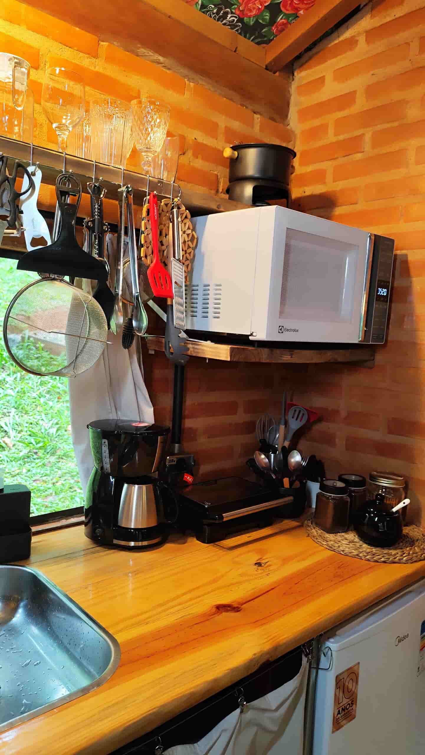 Bancada da cozinha da cabana organizada com itens essenciais de culinária, unindo funcionalidade e decoração rústica.