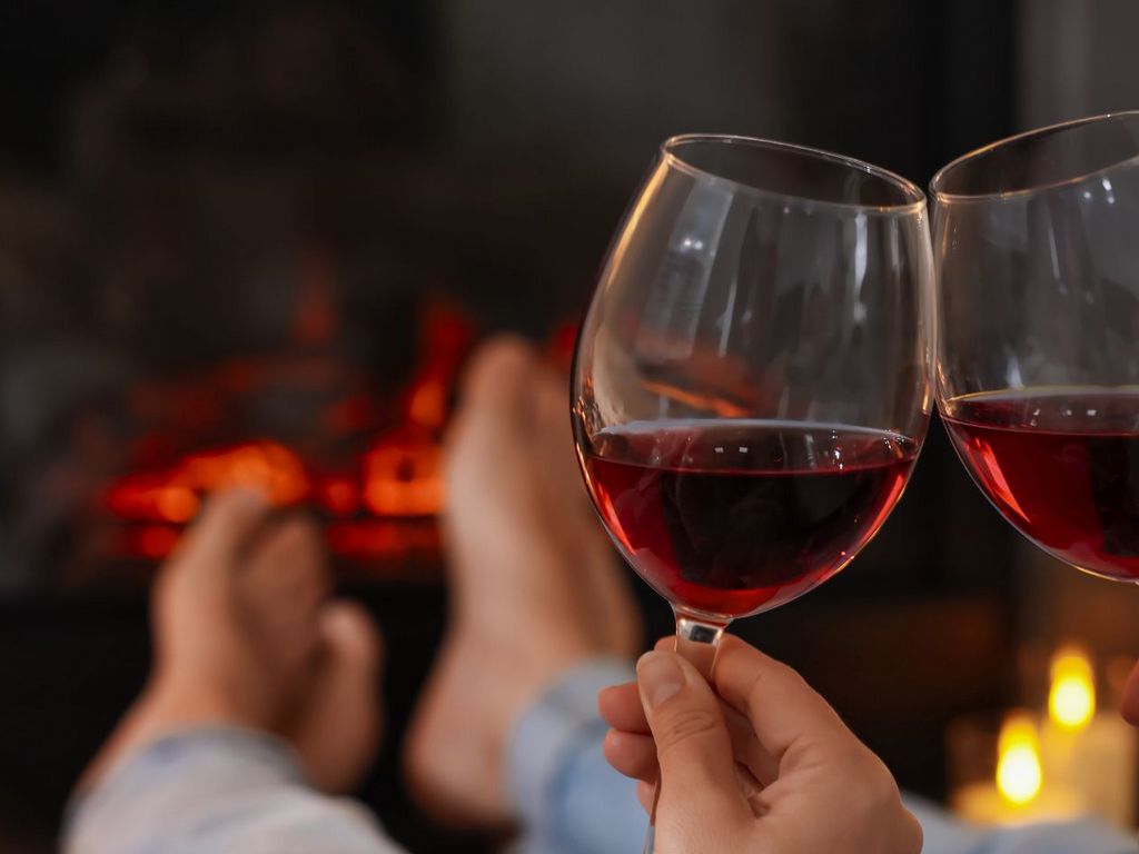 Duas taças de vinho próximas à lareira acesa, criando um cenário romântico e acolhedor para casais na cabana.