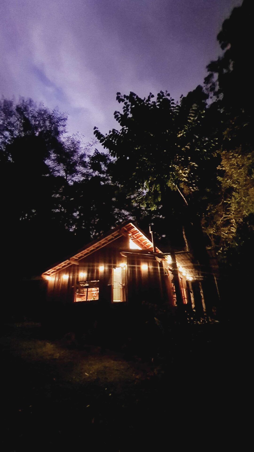 Vista externa das cabana Mayu do Sítio Cabanário durante o pôr do sol, com o céu entre a mata de Cunha.