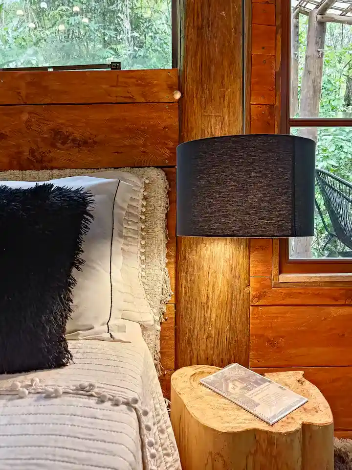 Cabeceira de cama decorada com almofadas pretas e creme com luminária preta pendente