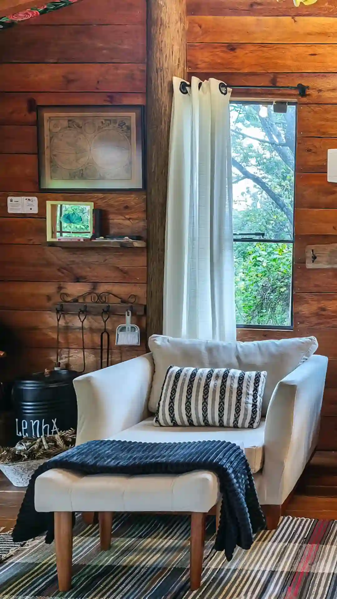 Poltrona Branca ao lado de lareira rustica em decoração preto e branco em cabana de madeira