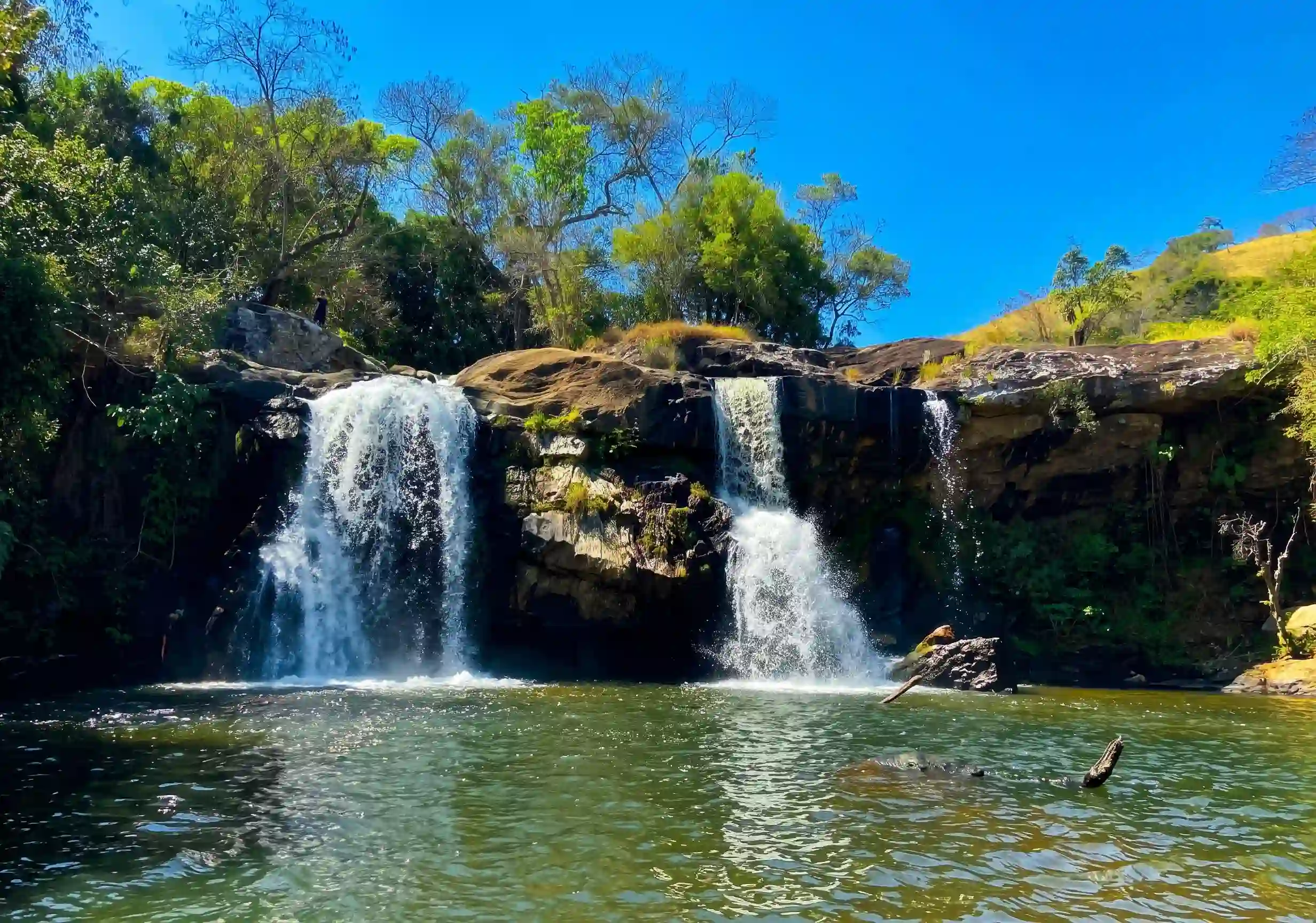 Cachoeira com duas quedas e piscina natural cercada pela paisagem rural de Cunha